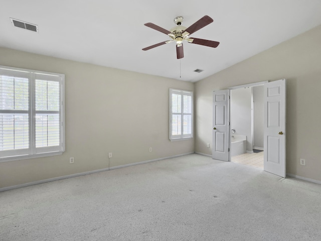 unfurnished bedroom featuring connected bathroom, light colored carpet, vaulted ceiling, and ceiling fan