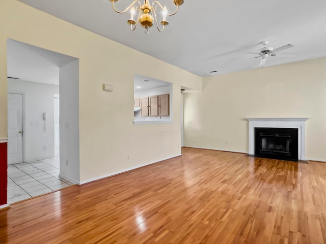 unfurnished living room featuring ceiling fan with notable chandelier and light wood-type flooring