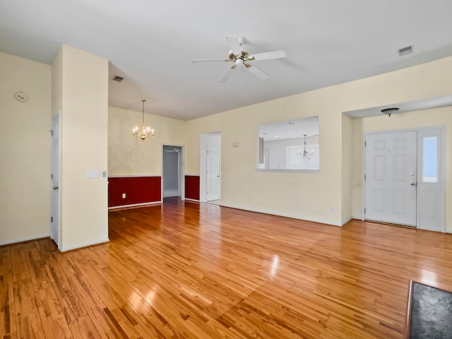 unfurnished living room featuring ceiling fan with notable chandelier and light hardwood / wood-style flooring