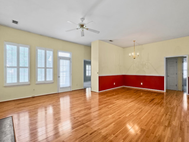 empty room featuring wood-type flooring and ceiling fan with notable chandelier