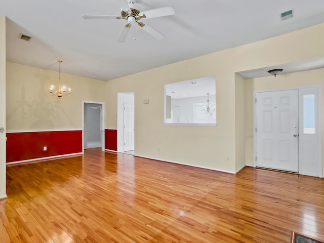 unfurnished living room with a wealth of natural light, hardwood / wood-style floors, and ceiling fan with notable chandelier