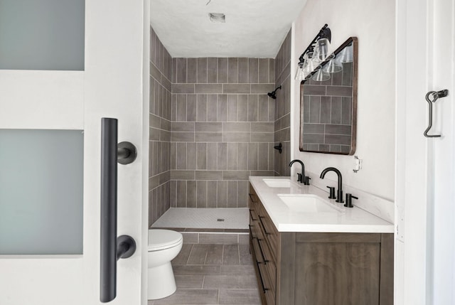 bathroom with a tile shower, vanity, and toilet