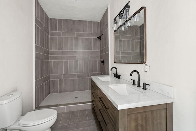 bathroom featuring vanity, toilet, and a tile shower