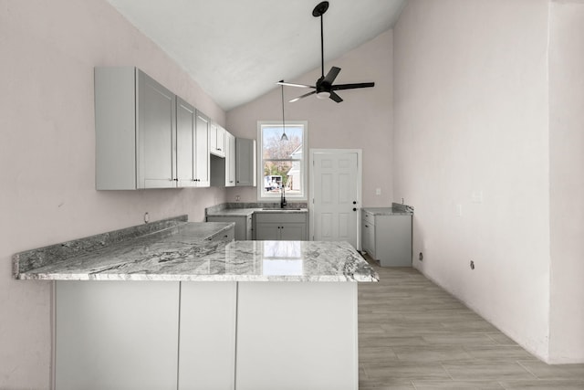 kitchen with gray cabinetry, light stone countertops, sink, ceiling fan, and kitchen peninsula