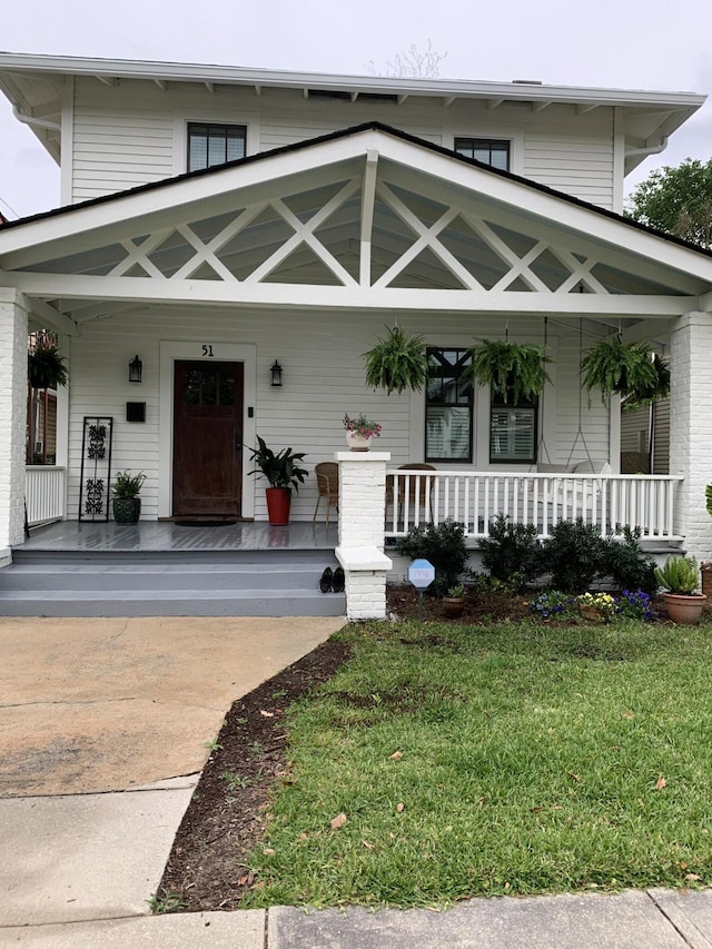 property entrance featuring a porch and a lawn