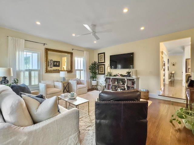 living room with light wood-type flooring, ceiling fan, and a wealth of natural light