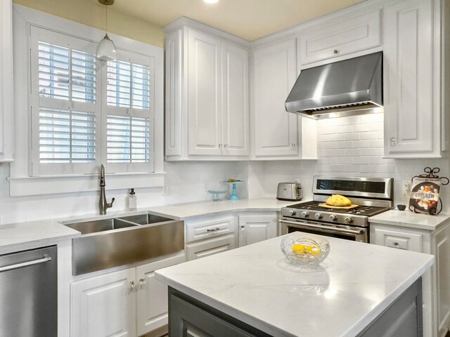 kitchen featuring exhaust hood, stainless steel appliances, white cabinetry, and decorative light fixtures