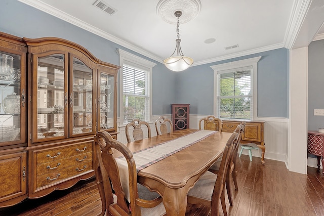 dining space with wainscoting, dark wood finished floors, crown molding, and plenty of natural light