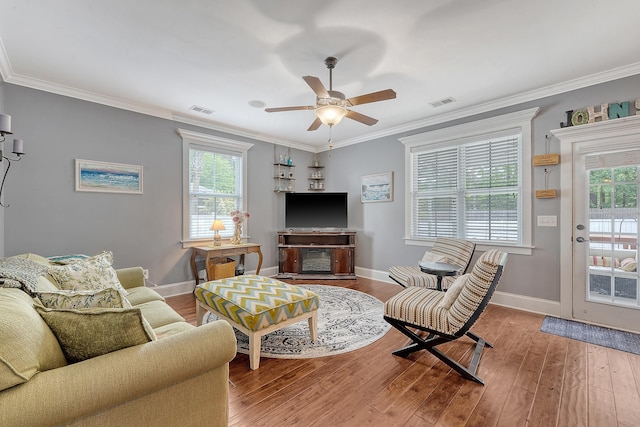 living room featuring a ceiling fan, plenty of natural light, wood finished floors, and crown molding
