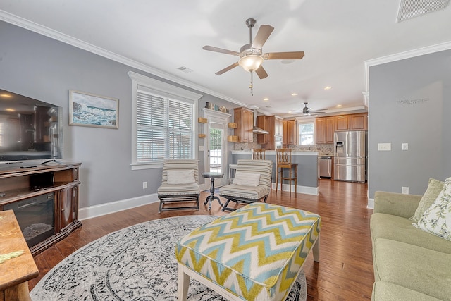 living area with a ceiling fan, ornamental molding, baseboards, recessed lighting, and wood finished floors