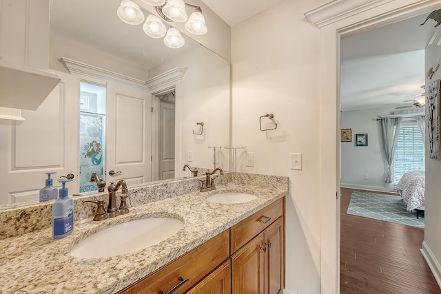 full bathroom featuring baseboards, double vanity, and wood finished floors
