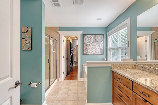 bathroom featuring a stall shower, tile patterned floors, vanity, baseboards, and a bathtub