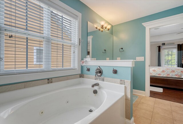 bathroom with ensuite bathroom, tile patterned floors, a jetted tub, and baseboards