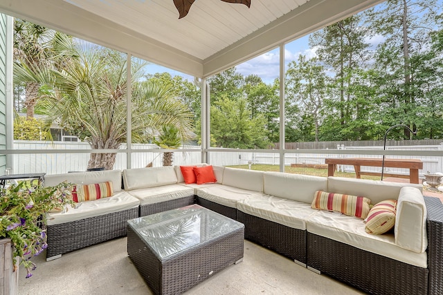 sunroom / solarium featuring an outdoor living space, ceiling fan, and view of wooded area
