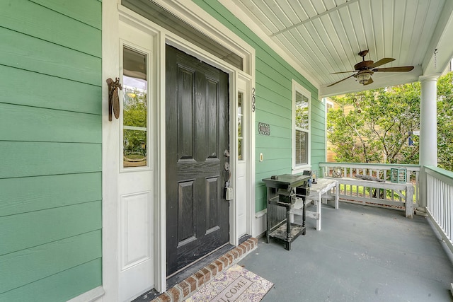 view of exterior entry with a porch and ceiling fan