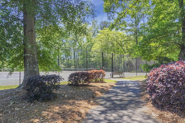 view of property's community with fence and a tennis court