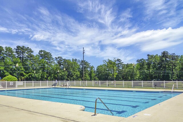 community pool with fence and view of scattered trees