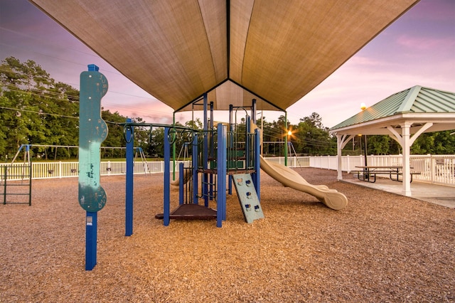 playground at dusk featuring fence and a gazebo
