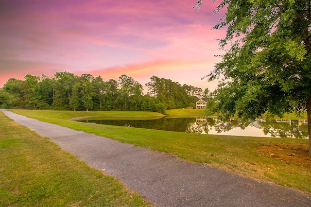surrounding community with a water view and a yard