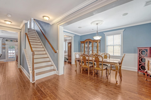 dining area with stairway, wainscoting, crown molding, and wood finished floors