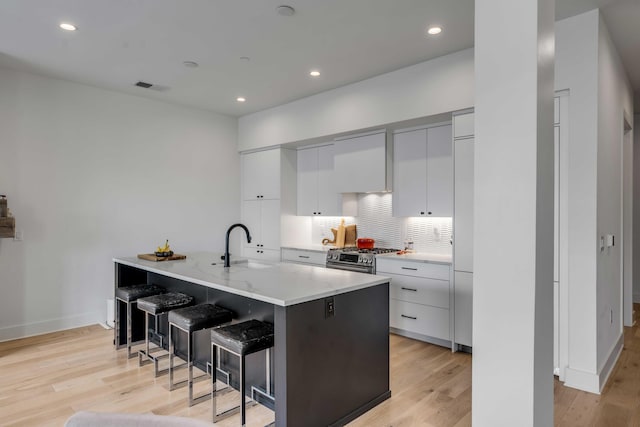 405 Spartina Ln Unit 405, Charleston, SC 29492 - kitchen with a sink, gas range, modern cabinets, a breakfast bar area, and tasteful backsplash