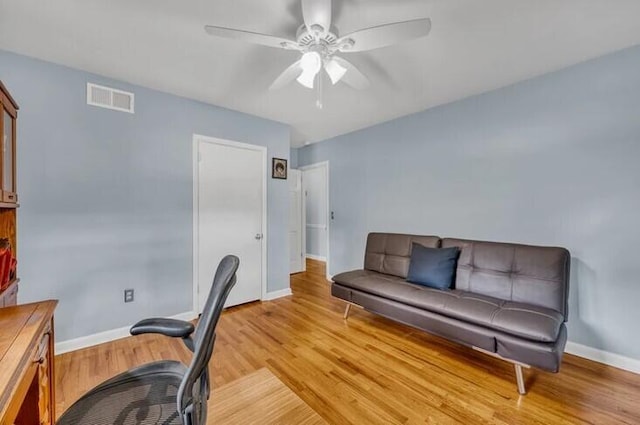 office featuring baseboards, a ceiling fan, visible vents, and light wood-style floors