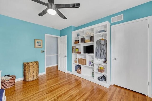 interior space featuring baseboards, wood finished floors, visible vents, and a ceiling fan