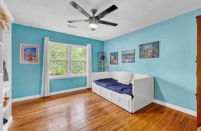 bedroom with wood finished floors, visible vents, baseboards, and ceiling fan