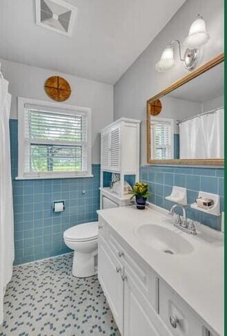 bathroom featuring tile walls, tile patterned flooring, walk in shower, vanity, and toilet