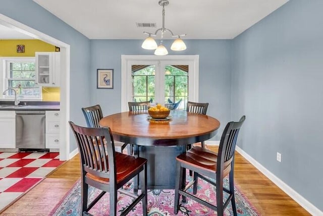 dining area featuring light hardwood / wood-style floors, an inviting chandelier, sink, and french doors