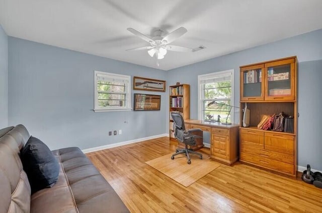 home office with light hardwood / wood-style floors and ceiling fan