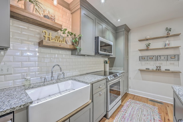 kitchen featuring appliances with stainless steel finishes, tasteful backsplash, and light stone counters