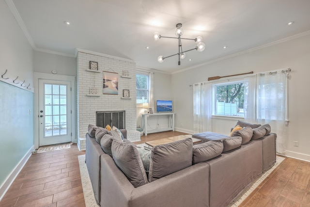 living room featuring a fireplace, an inviting chandelier, a wealth of natural light, and crown molding