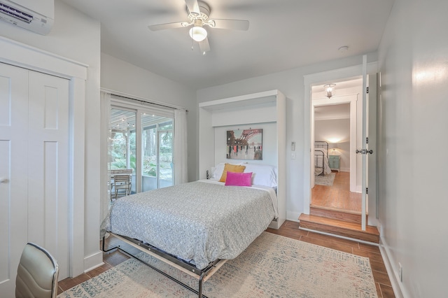 bedroom featuring a wall mounted air conditioner, wood-type flooring, access to outside, and ceiling fan