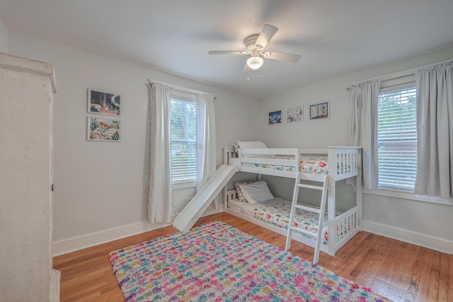 bedroom featuring ceiling fan, multiple windows, and light hardwood / wood-style flooring