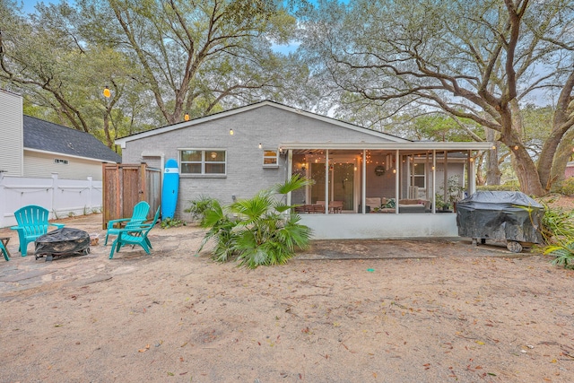 rear view of house featuring a fire pit and a sunroom