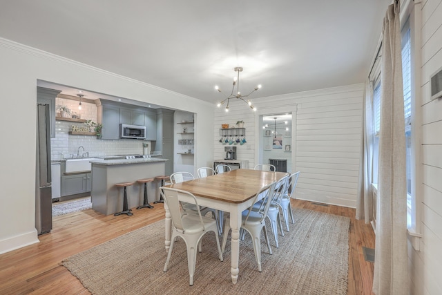 dining space featuring light hardwood / wood-style floors, crown molding, sink, and a chandelier