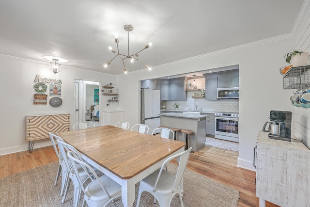 dining space with ornamental molding, a notable chandelier, and light wood-type flooring