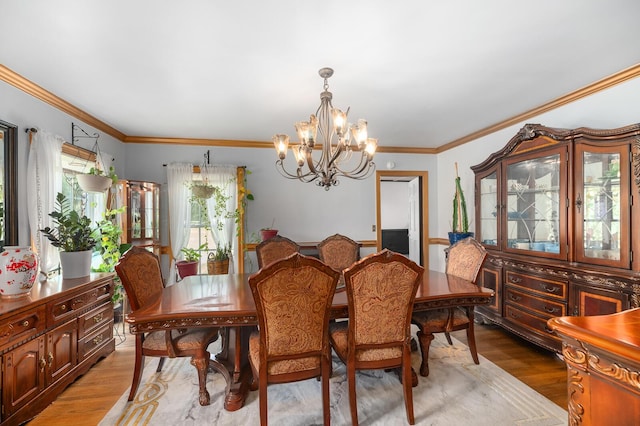 dining area with hardwood / wood-style flooring, crown molding, and an inviting chandelier