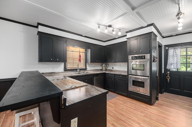 kitchen with sink, appliances with stainless steel finishes, backsplash, light hardwood / wood-style floors, and kitchen peninsula