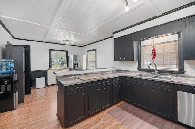 kitchen featuring sink, light hardwood / wood-style flooring, kitchen peninsula, and appliances with stainless steel finishes