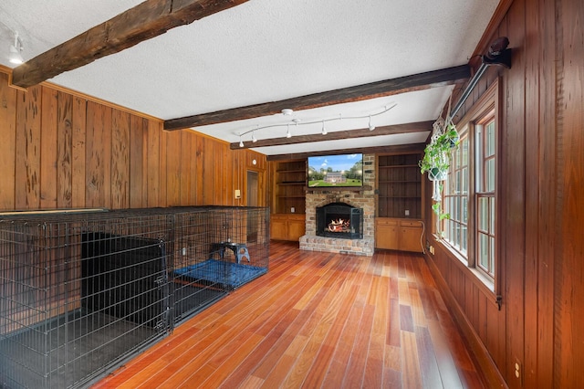 unfurnished living room with a brick fireplace, hardwood / wood-style floors, a textured ceiling, and wood walls