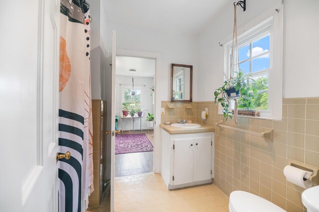 bathroom with vanity, tile walls, a shower with shower curtain, and toilet