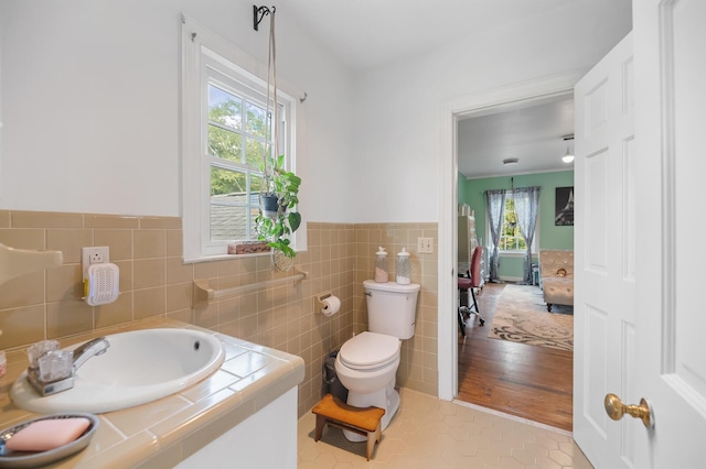 bathroom with tile walls, sink, plenty of natural light, and toilet