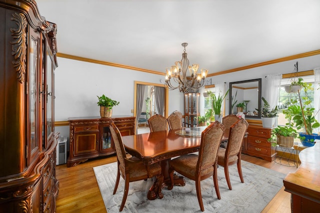 dining area with an inviting chandelier, ornamental molding, and light wood-type flooring