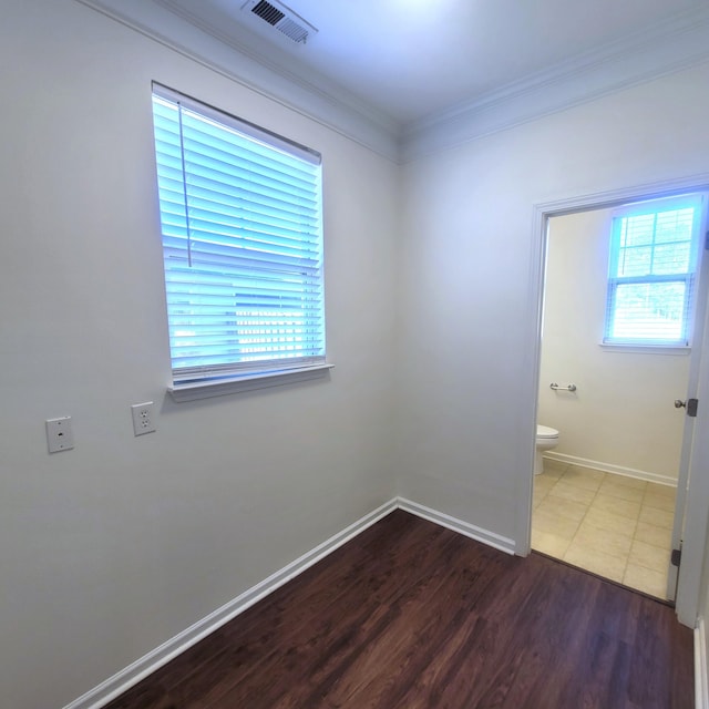 spare room with baseboards, visible vents, wood finished floors, and ornamental molding