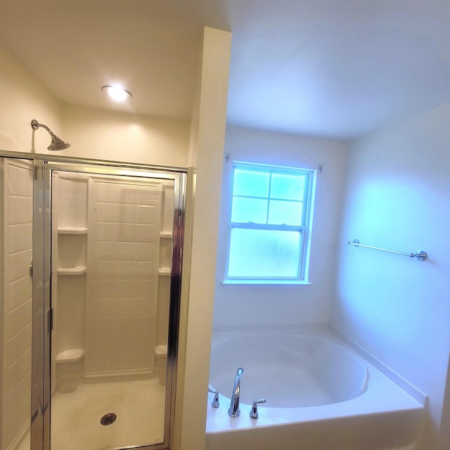 bathroom featuring a stall shower and a bath