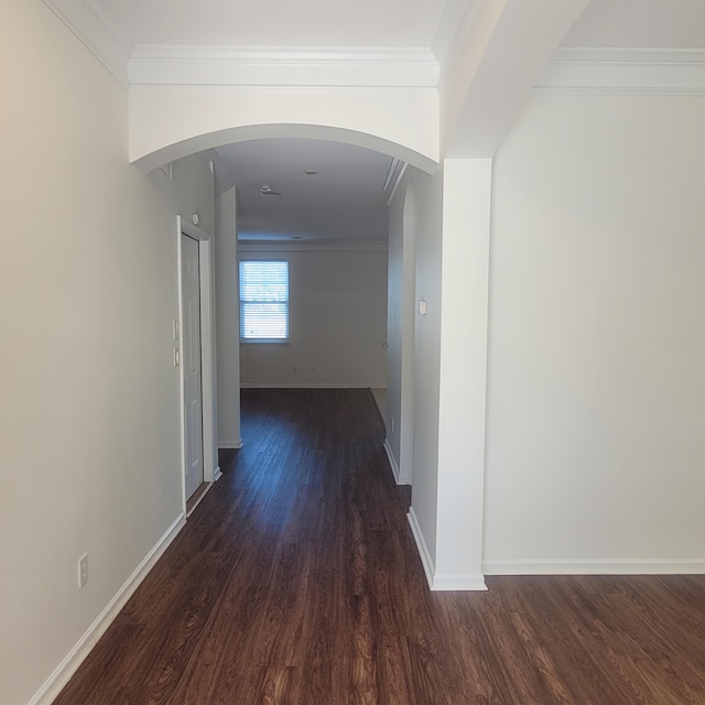 hallway with dark wood-style floors, baseboards, arched walkways, and ornamental molding