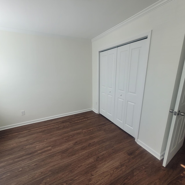 unfurnished bedroom featuring ornamental molding, a closet, dark wood finished floors, and baseboards