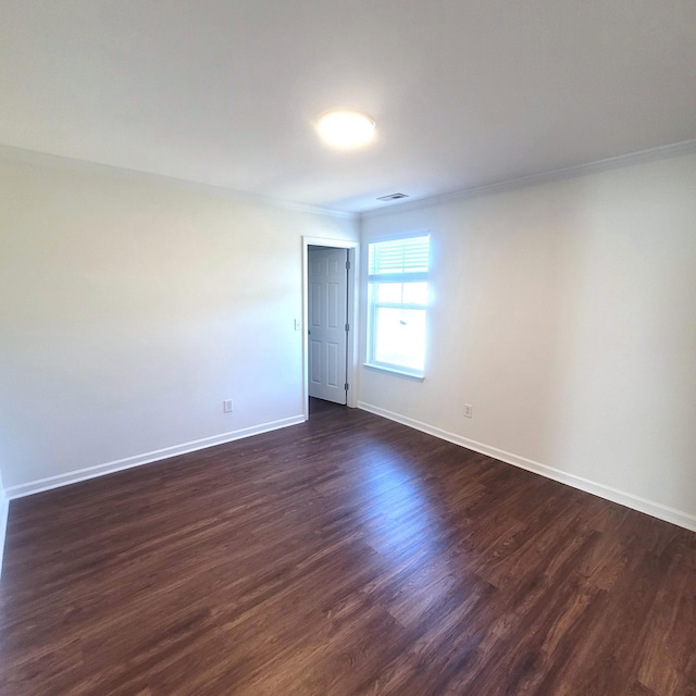 empty room featuring baseboards, visible vents, dark wood-type flooring, and ornamental molding